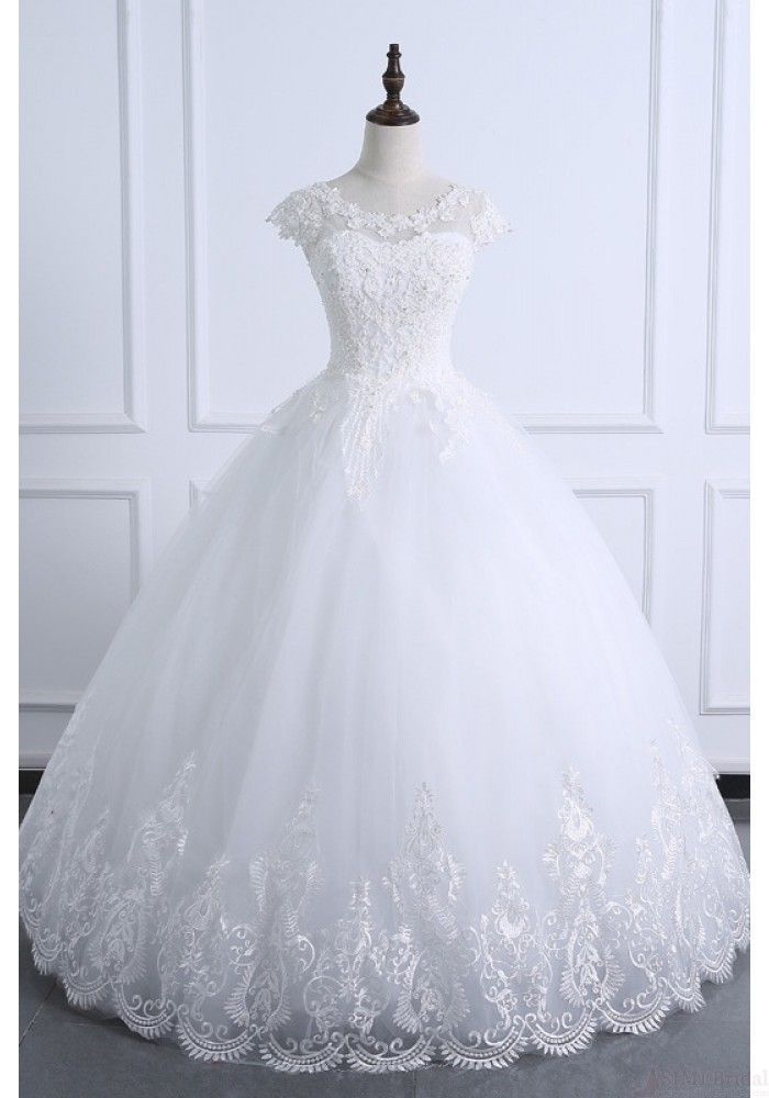 a white wedding dress on a mannequin stand in front of a white wall