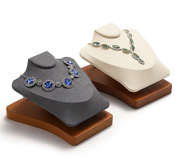 two hats and necklaces on display on wooden bases, one is white with blue stones