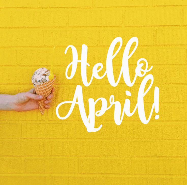 a person holding an ice cream cone in front of a yellow wall with the words hello april written on it