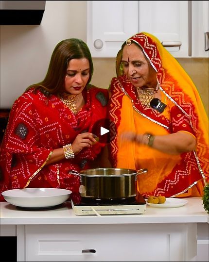 two women in red and yellow outfits cooking on a stove top with a white bowl next to them