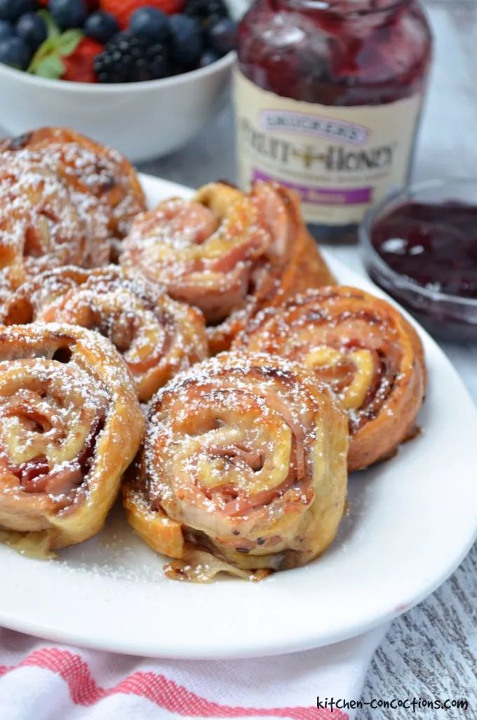 several pastries on a white plate with fruit in the background