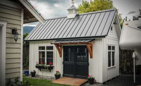 a small white shed with a black door