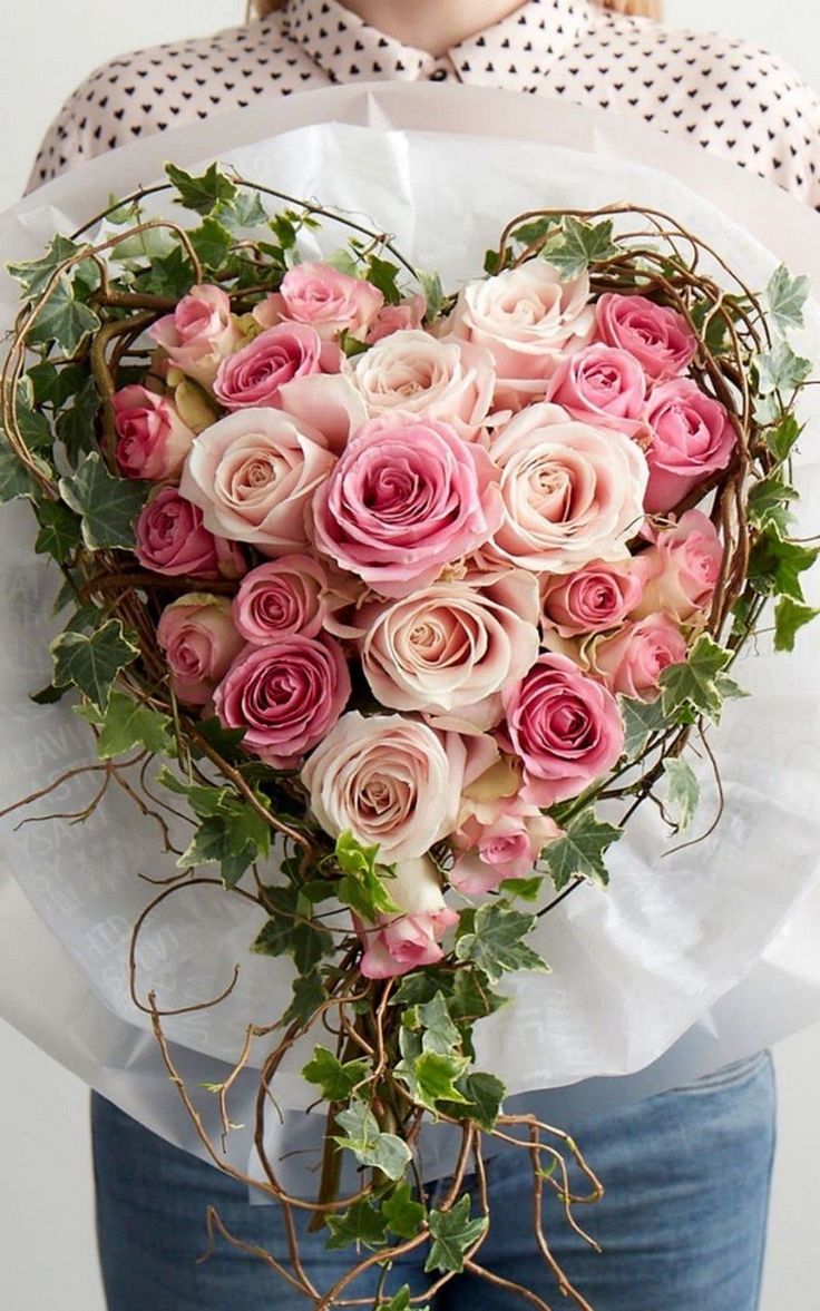 a woman holding a heart shaped bouquet of roses