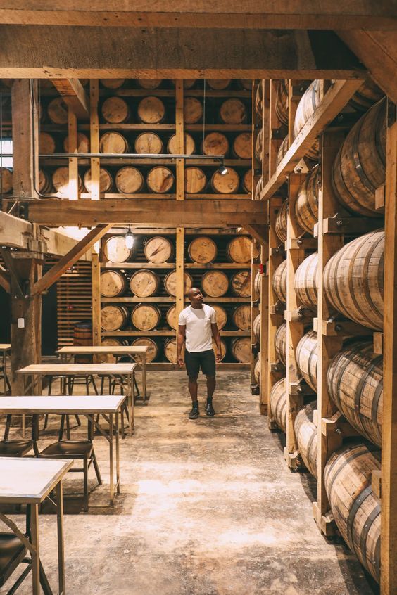 a man standing in the middle of a room filled with wooden barrels and tables next to each other