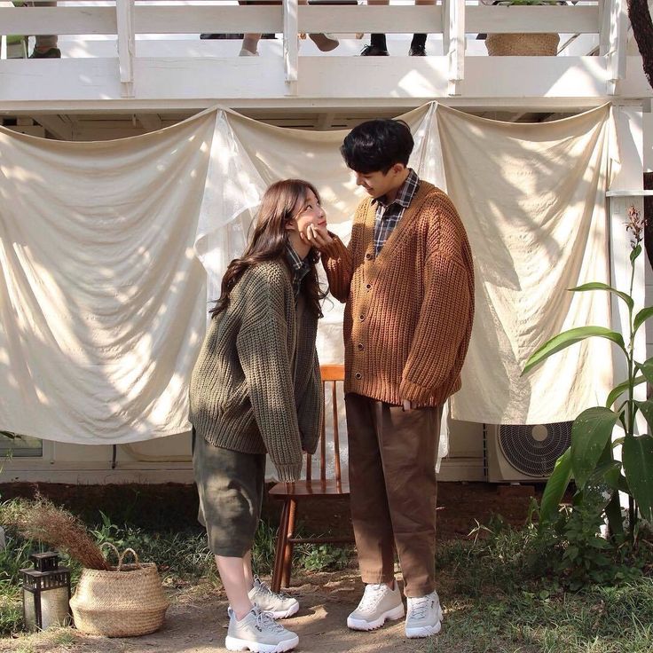 two people standing next to each other in front of a white tent with curtains on it