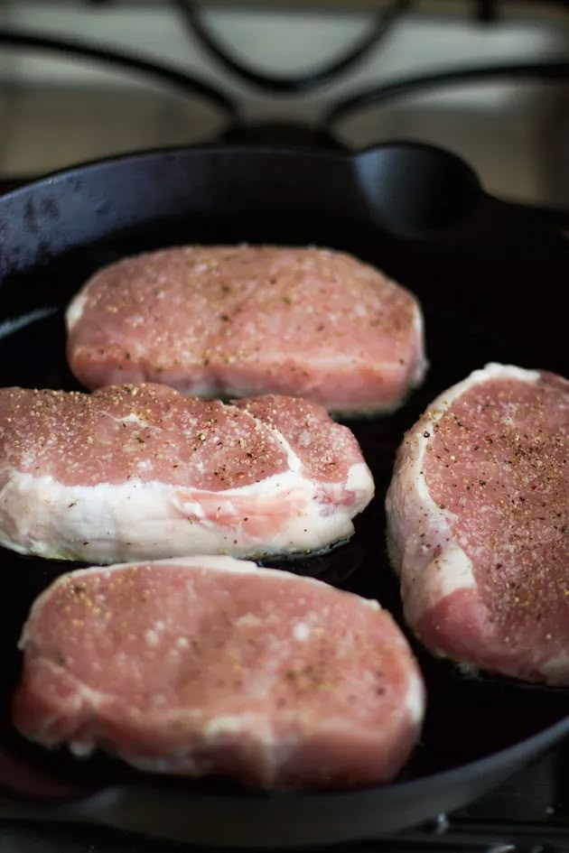 four raw meats are cooking in a skillet