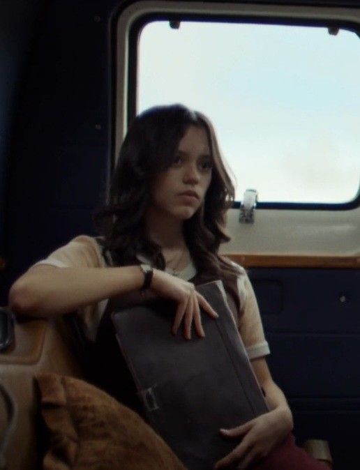 a woman sitting on a train holding a book in her lap and looking out the window