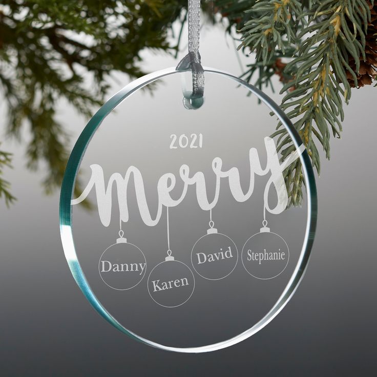 a glass ornament hanging from a tree with the words merry written on it