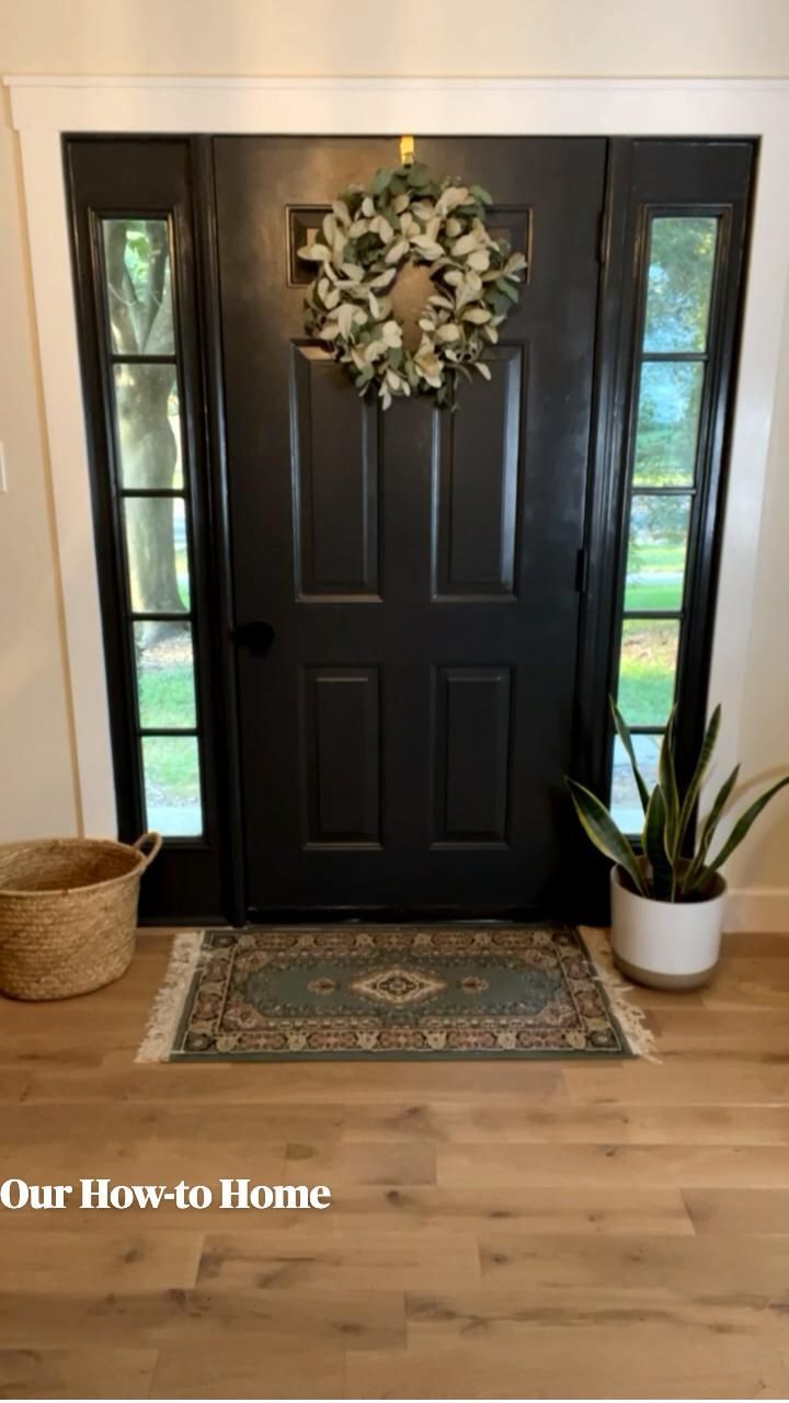 a black front door with a wreath on it and a potted plant next to it