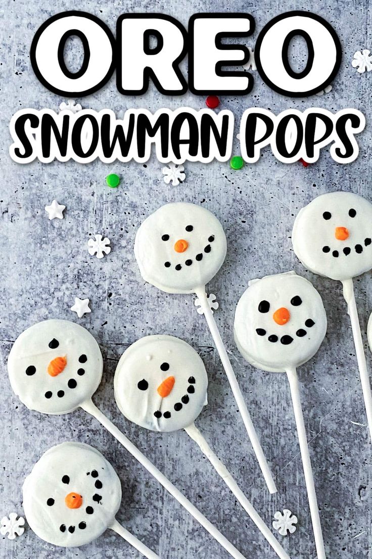 snowman pops with white frosting and orange noses are on a gray surface surrounded by snowflakes