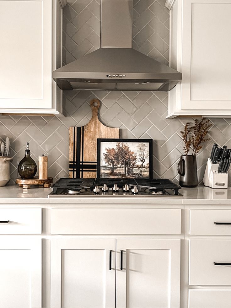 a stove top oven sitting inside of a kitchen next to white cupboards and drawers