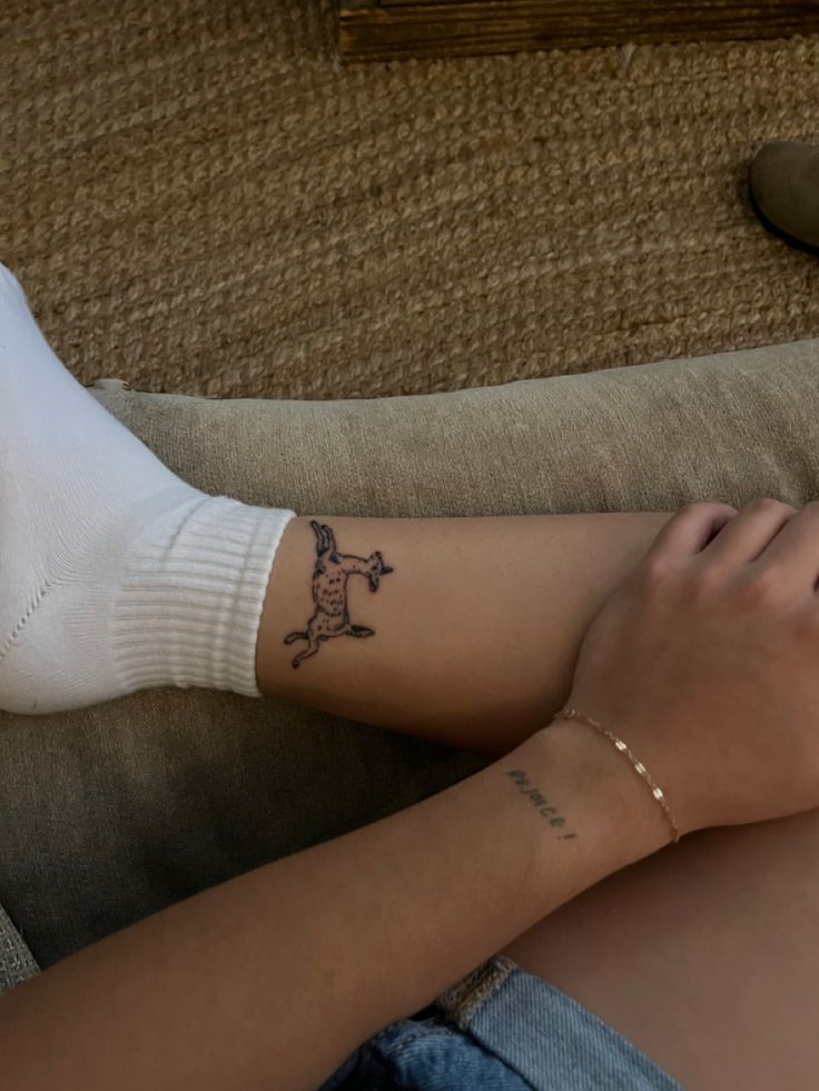 a woman with a tattoo on her arm sitting on a couch next to a cat