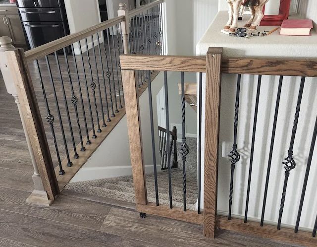 a dog is standing at the top of a stair case in a house with wood and metal railings