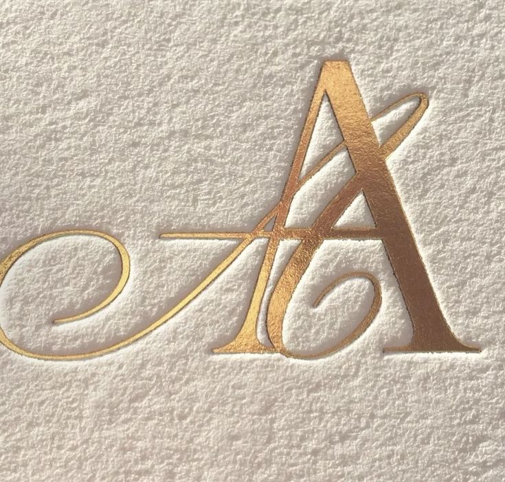 the letter a is made up of gold foil on white paper with an elegant design