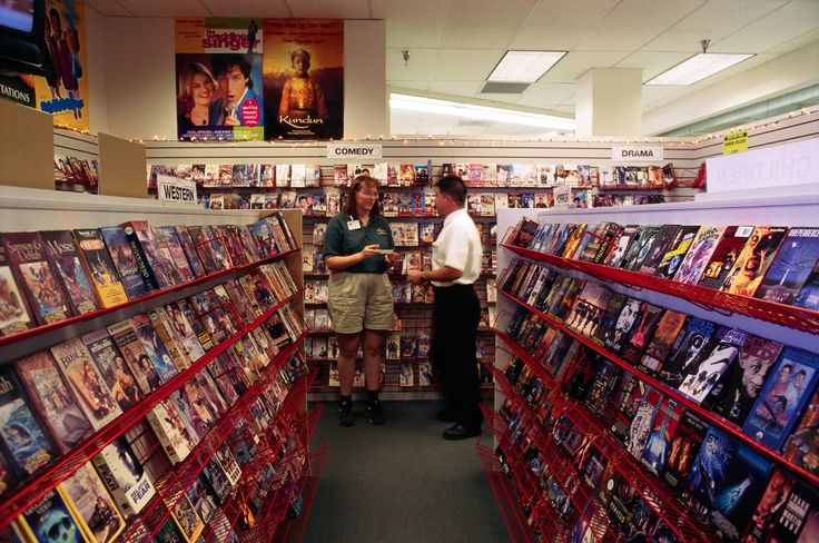 two people are standing in the aisle of a book store, surrounded by rows of books