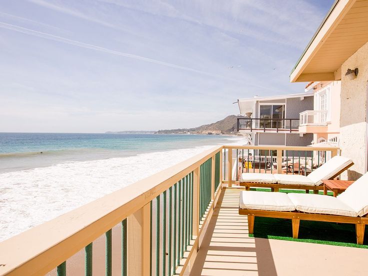 a balcony overlooking the ocean with chaise lounges