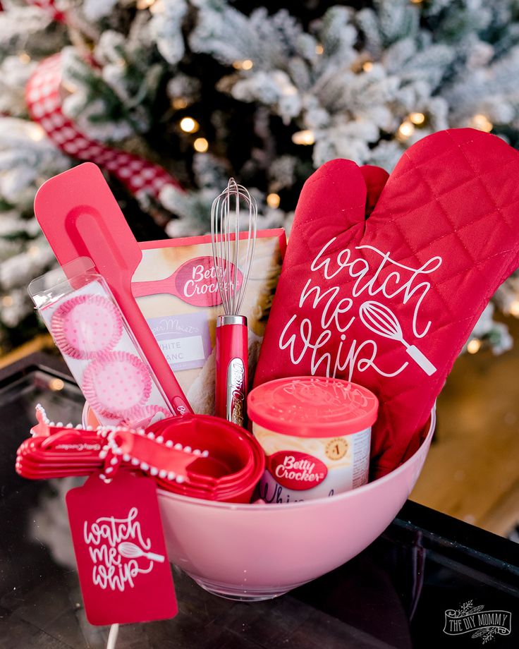 a pink bowl filled with baking supplies next to a christmas tree