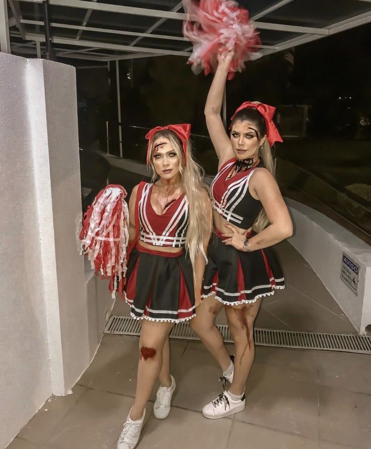 two young women dressed in cheerleader costumes posing for the camera with pom poms