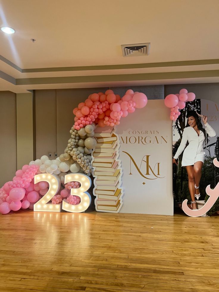 a woman standing in front of a large number sign with balloons on top of it