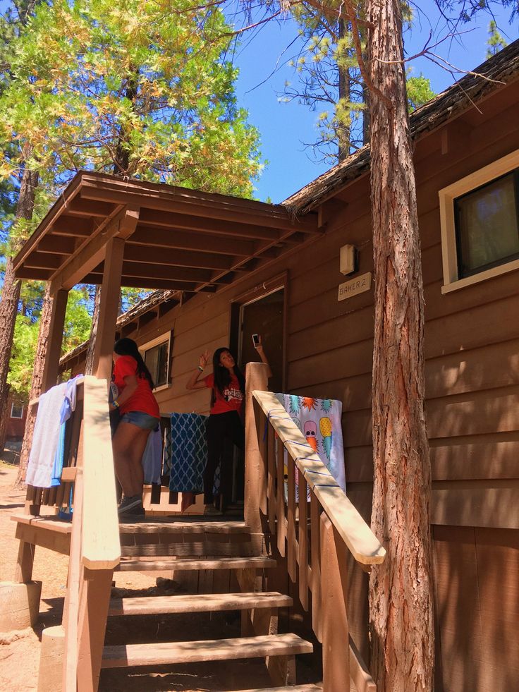 three people standing on the porch of a cabin