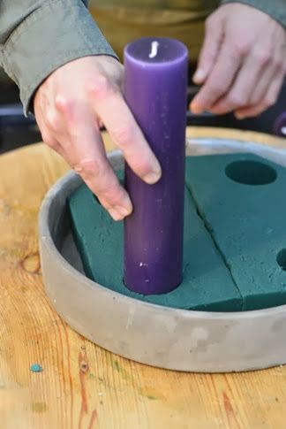 a person is holding a candle in front of a purple object on a wooden table