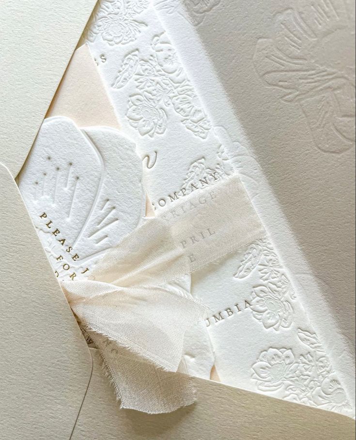 the inside of a wedding card with white paper and ribbon on it's side