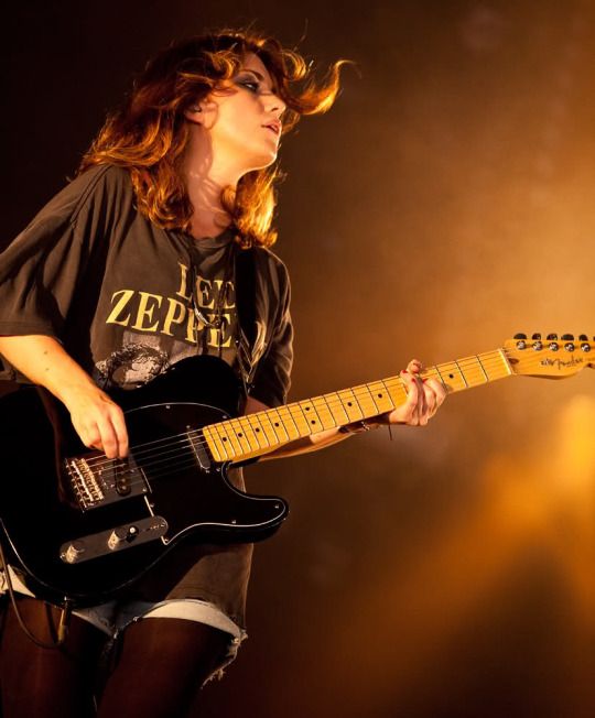 a woman playing an electric guitar on stage