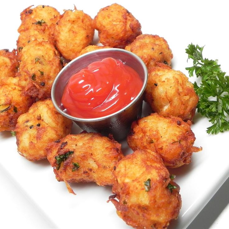 some fried food on a white plate with ketchup and garnishes