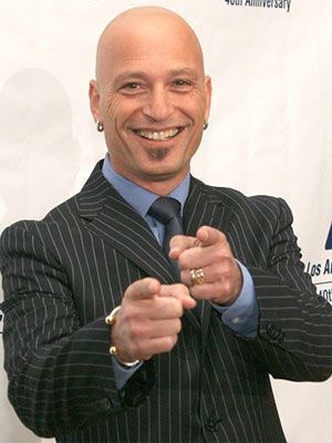 a bald man in a suit and tie posing for the camera with his hands together