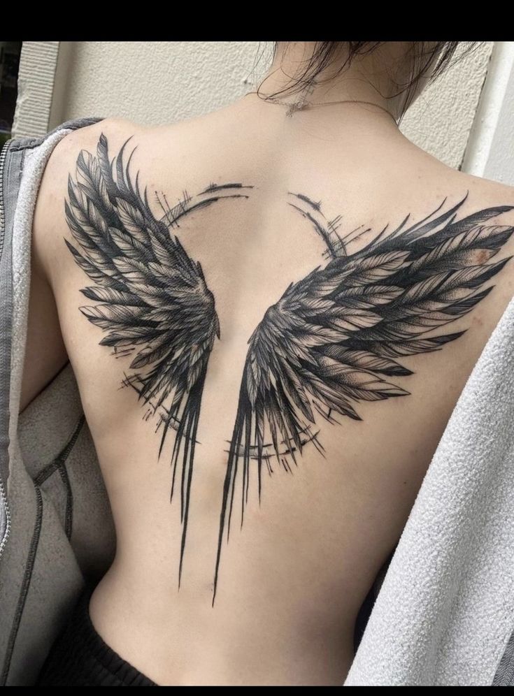 a woman's back with an angel wing tattoo on it