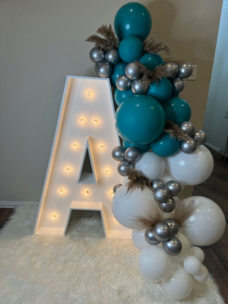 the letter a is decorated with silver and white balloons, feathers, and letters that spell out'a '