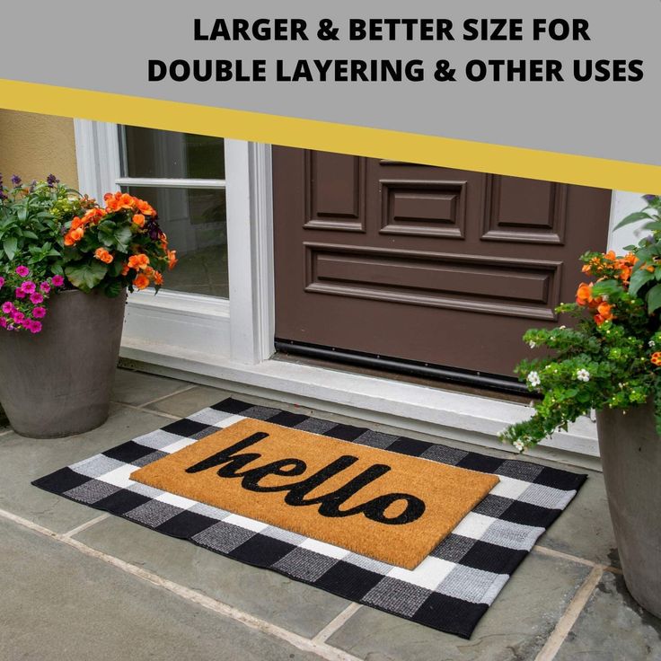 a door mat with the word hello on it and two potted plants next to it