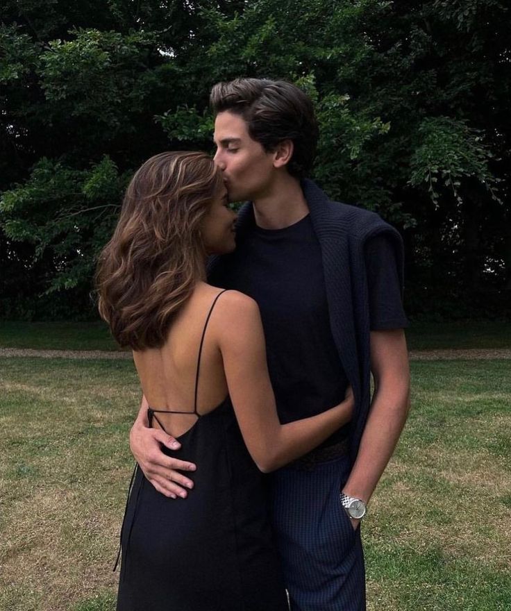 a young man and woman are kissing in the grass