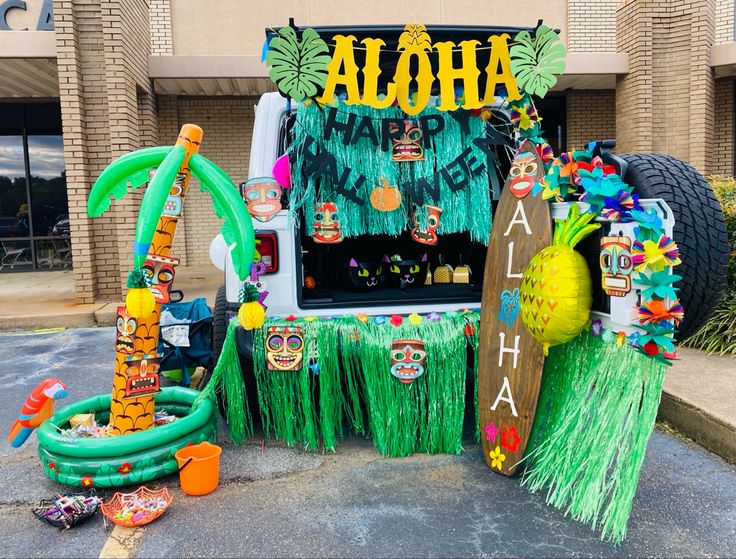 a vehicle decorated with hula decorations in front of a building that says aloha