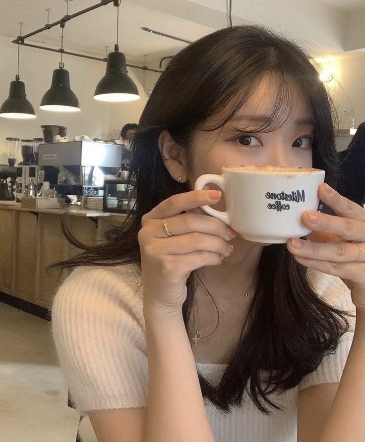 a woman holding a coffee cup in front of her face