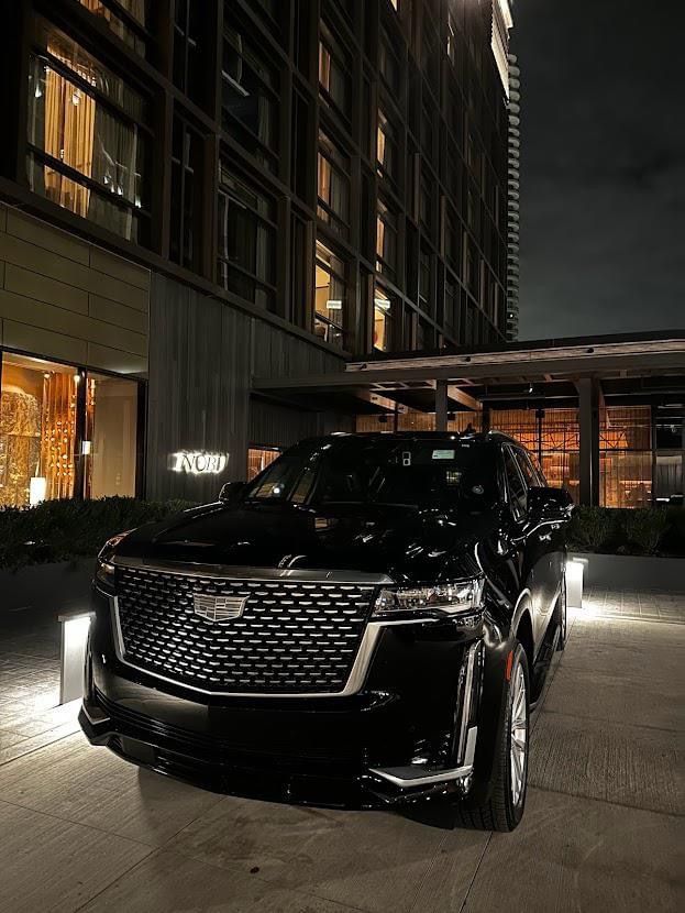 a black cadillac parked in front of a building at night