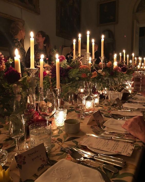 a long table is set with many candles and place settings for the dinner guests to enjoy