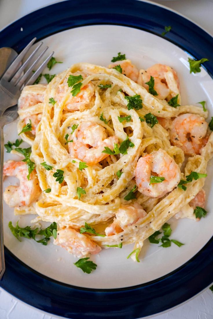 pasta with shrimp, parsley and parsley on a white plate next to a fork