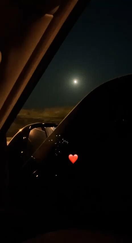 the view from inside a car at night with a full moon in the sky behind it