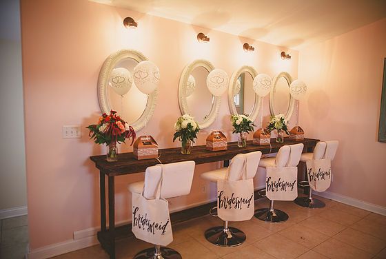 a row of chairs sitting in front of a mirror on top of a counter next to vases filled with flowers