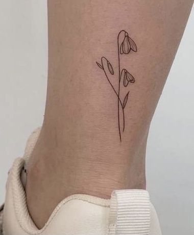 a small tattoo on the ankle of a woman's foot with flowers in it