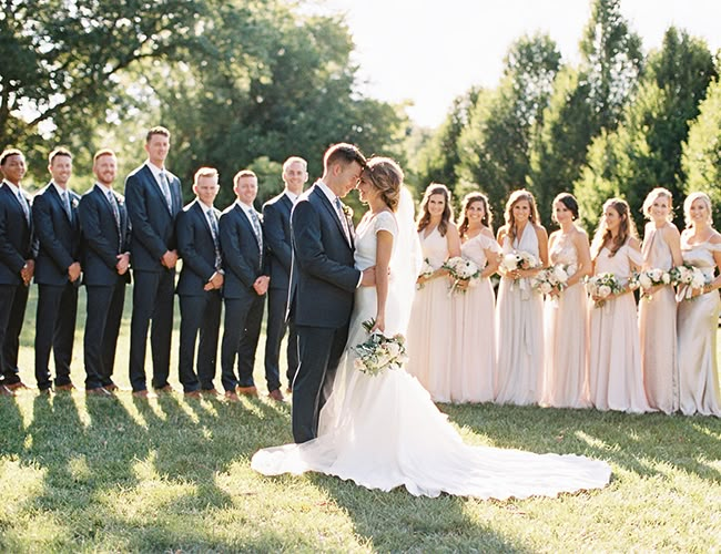 a bride and groom kissing in front of their wedding party