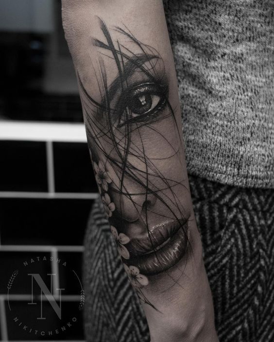 a woman's arm with a black and white tattoo design on the left forearm