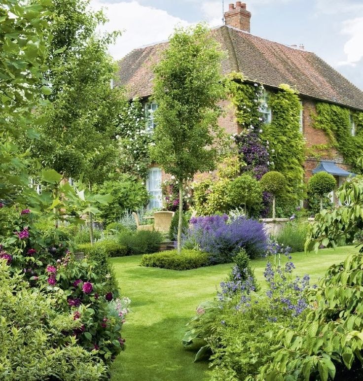 a lush green yard with lots of flowers and plants growing on the side of it