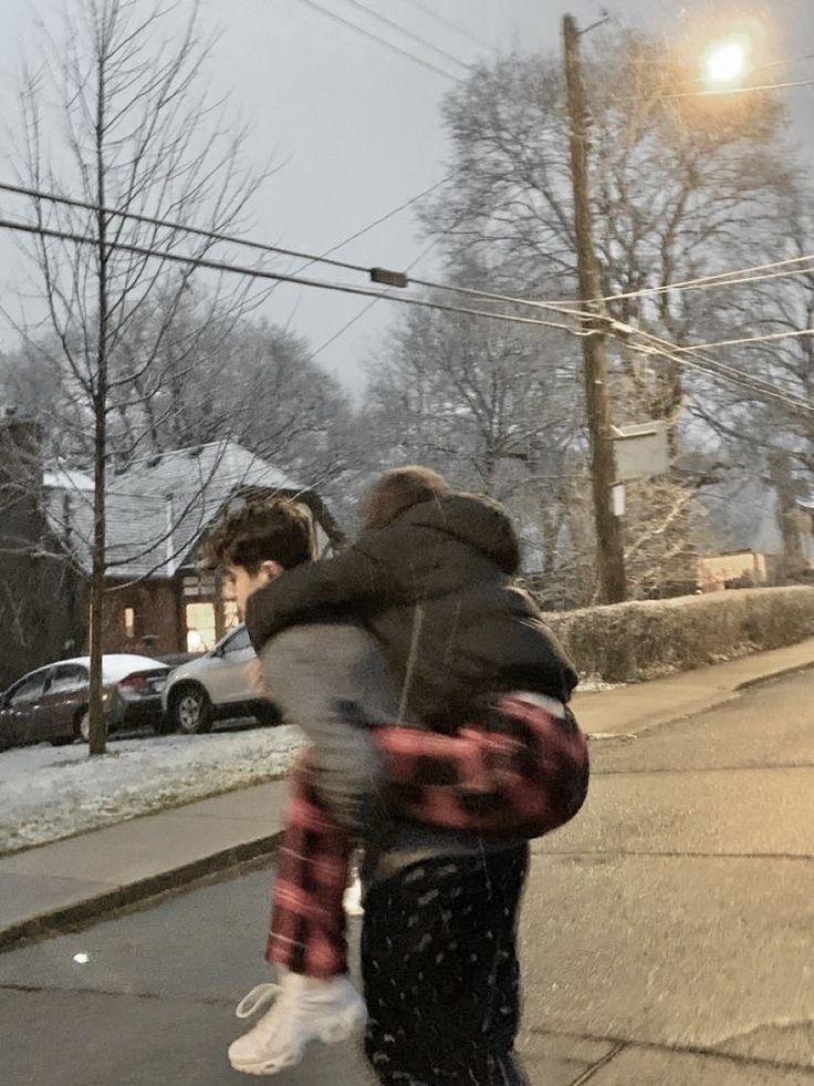 two people are walking down the street with snow on their feet and one is carrying a child