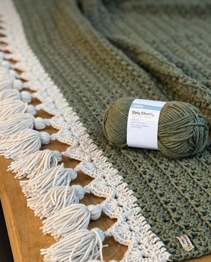 a ball of yarn sitting on top of a table next to a green and white blanket