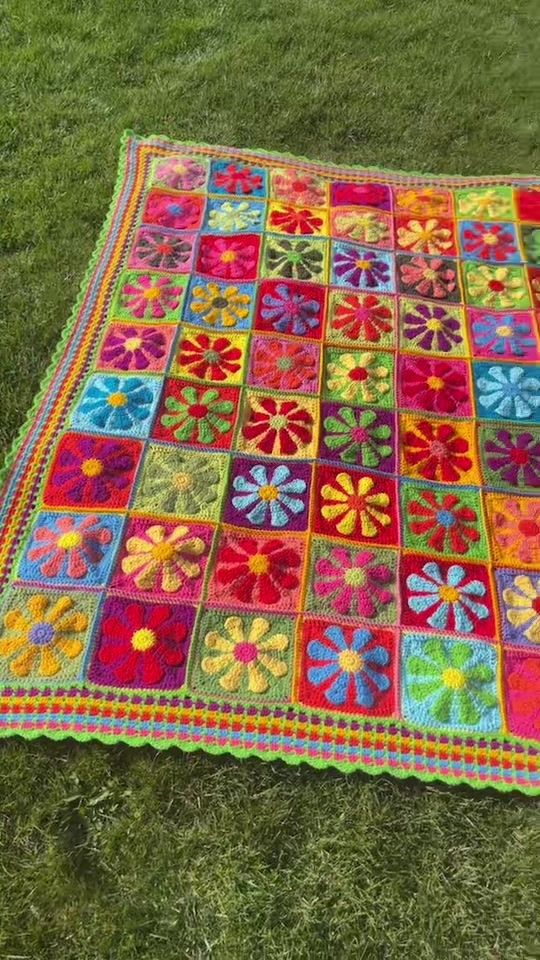 a multicolored quilt is laying on the grass