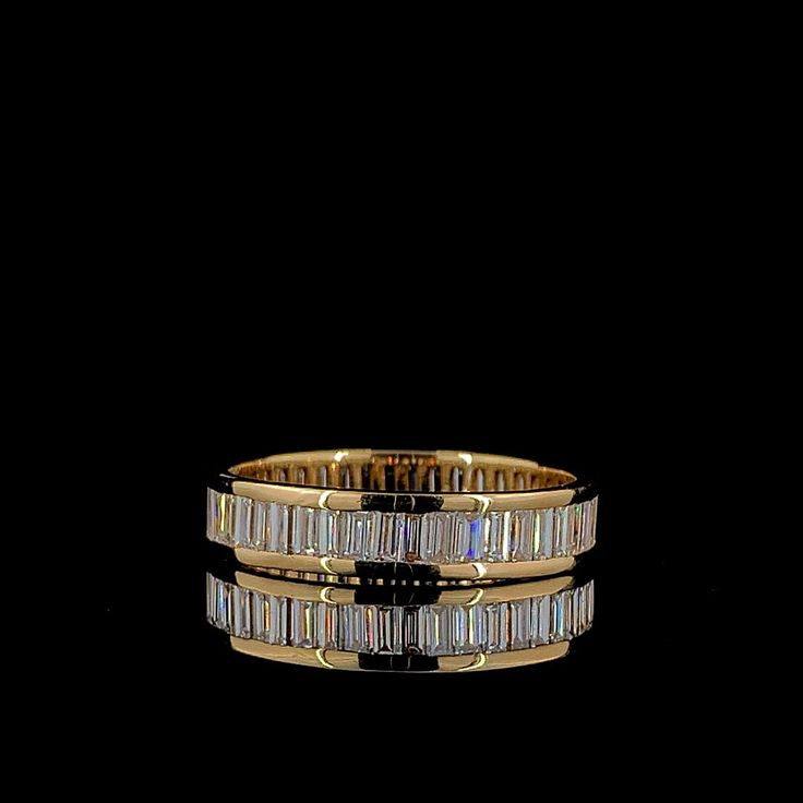 two gold rings with baguettes and diamonds on them, against a black background