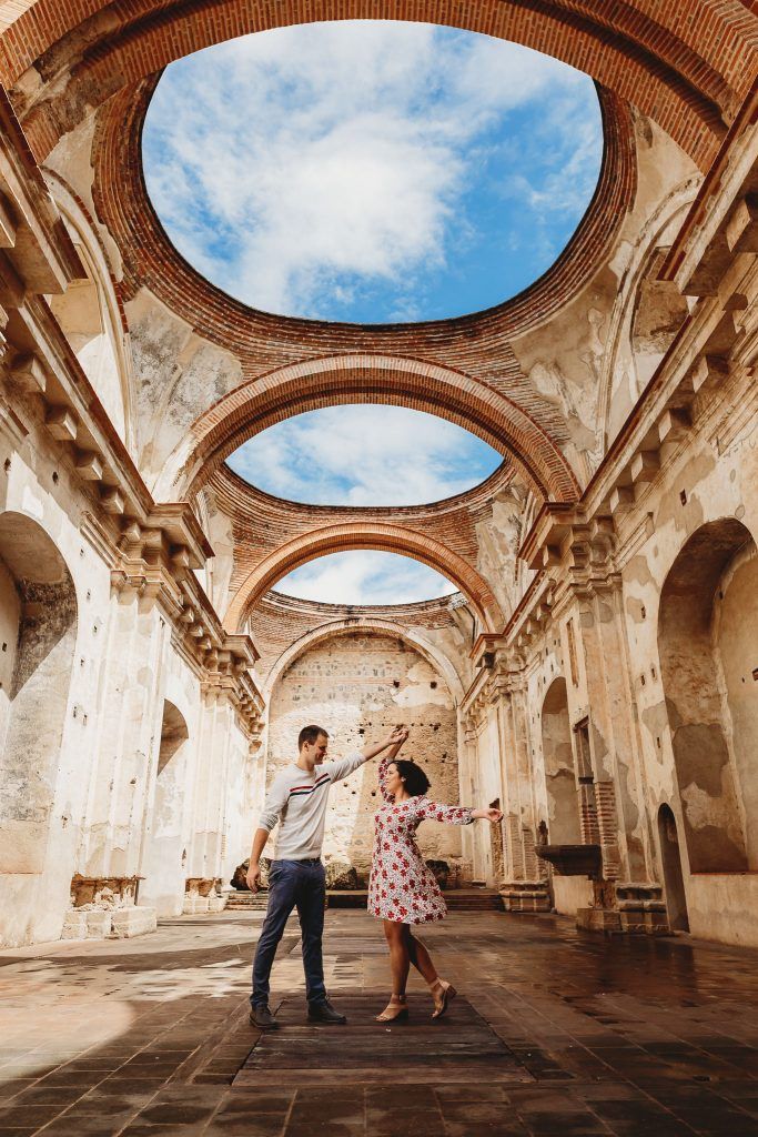 a man and woman are dancing in an old building with skylights above their heads