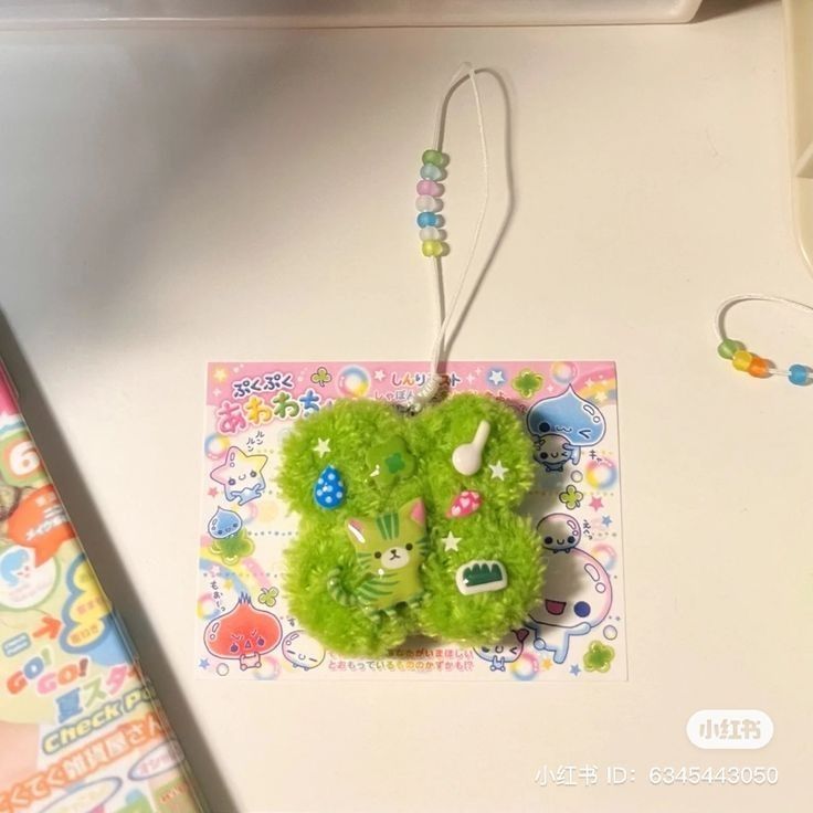 a green stuffed animal hanging from a cord on a white surface with other items around it